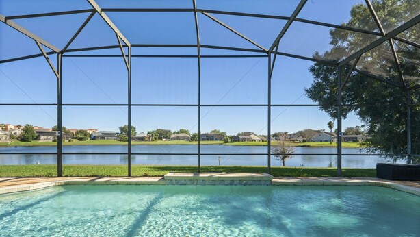 A swimming pool with a clear view of a lake and houses in the background.