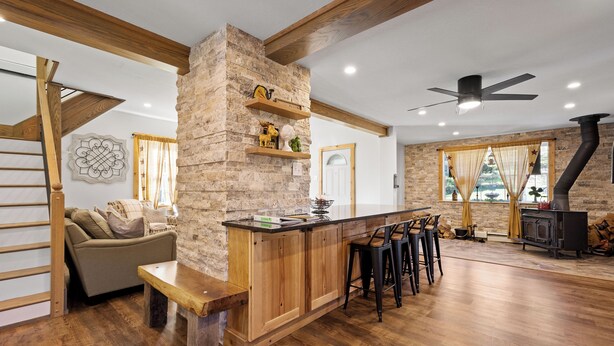 A spacious living area with a wooden bar, stone accent wall, and a fireplace. - Indian Head Retreat  (Indian Head)