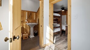 A wooden interior with a white sink, wooden cabinets, and a bed with white bedding. - Indian Head Retreat  (Indian Head)