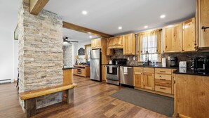A spacious kitchen with wooden cabinets, a stone accent wall, and modern appliances. - Indian Head Retreat  (Indian Head)