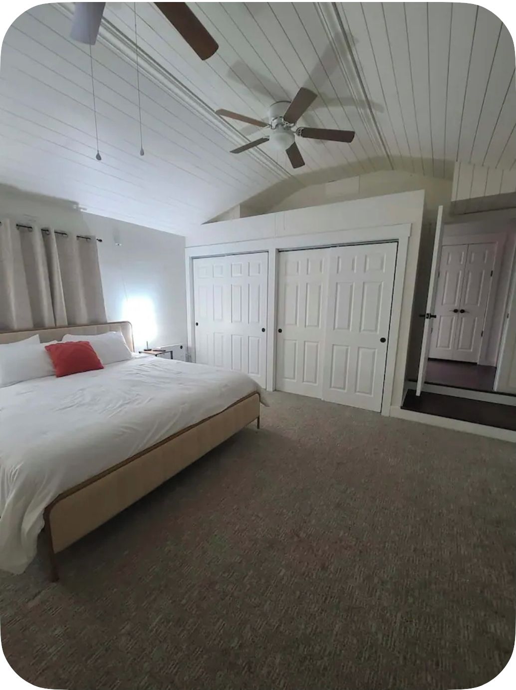 A bedroom with a bed, a ceiling fan, and two doors.