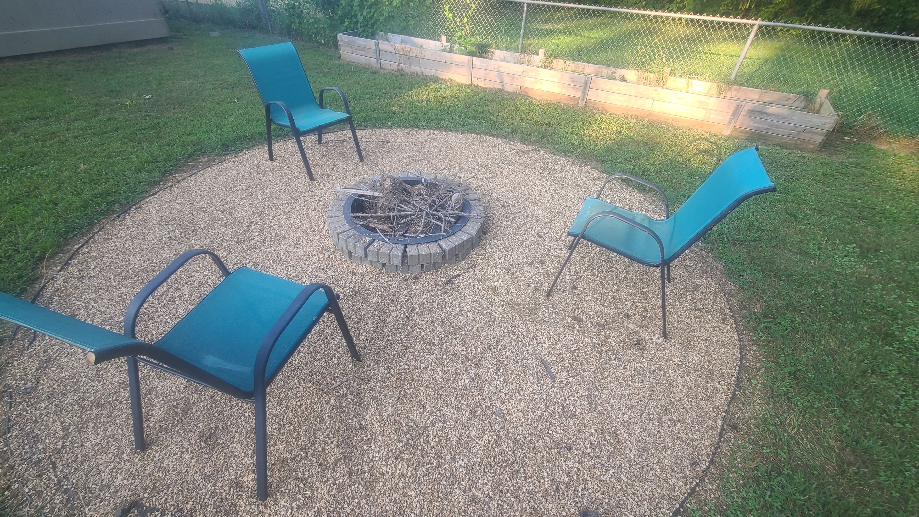 A circular seating area with four chairs around a fire pit.