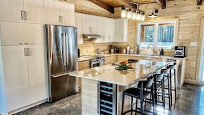 Cocina moderna con electrodomésticos de acero inoxidable, armarios de madera y una isla central con taburetes de bar.