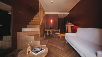 Uma sala de estar moderna com escada de madeira, um sofá, uma mesa de centro redonda e um espaço de jantar.