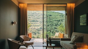 A modern hotel room with a balcony, a sofa, a chair, and a small table. - Torel Quinta da Vacaria - Douro Valley (Peso da Régua)