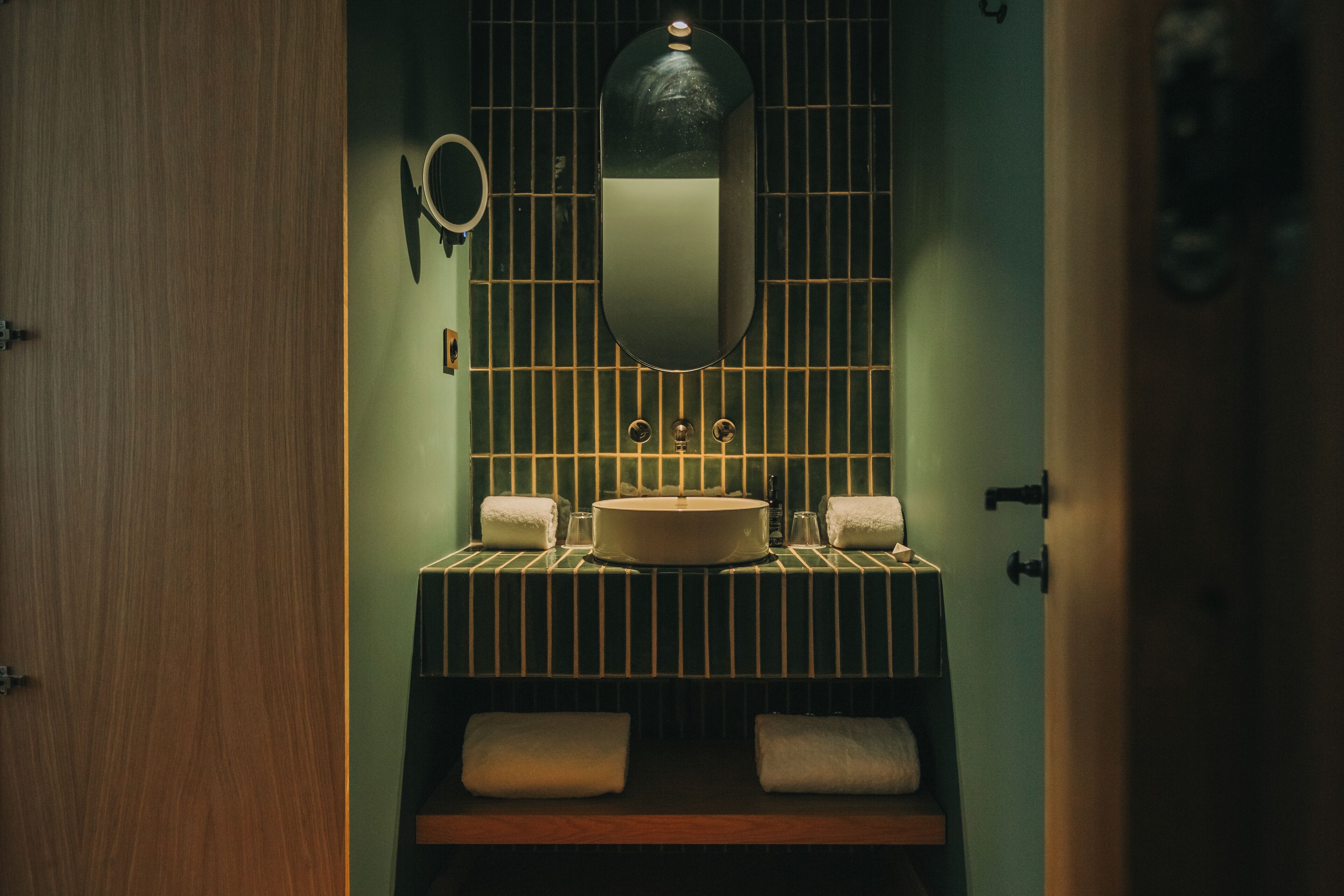 A bathroom with a sink, mirror, and two towels on a shelf.