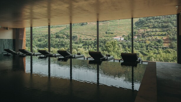 An indoor swimming pool with lounge chairs and a view of a vineyard. - Torel Quinta da Vacaria - Douro Valley (Peso da Régua)