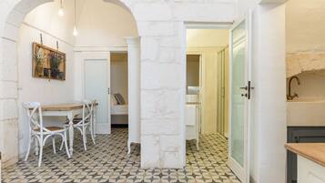 Un'area pranzo con tavolo e sedie, pavimento piastrellato e una porta che conduce in un'altra stanza.