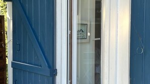 A window with blue shutters, a white door, and a small mailbox. - Cabane Edena, Terrasse Ombragée Jardin Vélos Wifi à 350m de la Plage du Mauret (Andernos-les-Bains)
