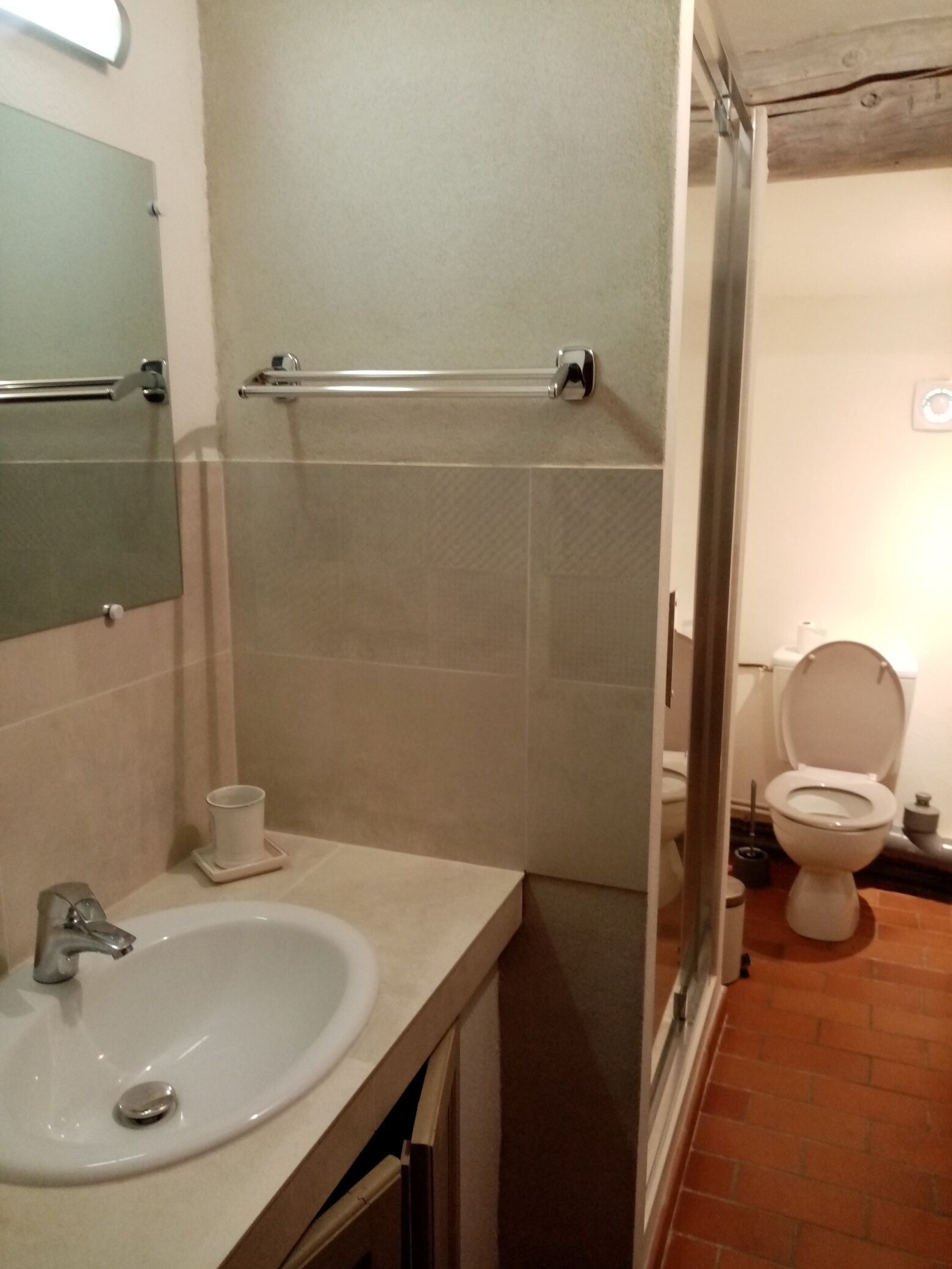 Un baño con lavamanos, espejo, toallero y retrete.