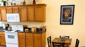 A kitchen with wooden cabinets, a white stove, and a dining table with chairs. - Cozy Cajun

 (Ponchatoula)