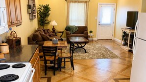 A kitchen with a stove, dining table, and chairs, a living area with a sofa and a TV, and a ceiling fan. - Cozy Cajun

 (Ponchatoula)