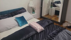 Une chambre à coucher avec un lit, une table de chevet, un miroir et une plante en pot.