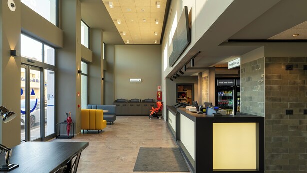 A modern lobby with a reception desk, seating area, and a food and drink station. - a&o Hostel Firenze Campo Di Marte (Florence)