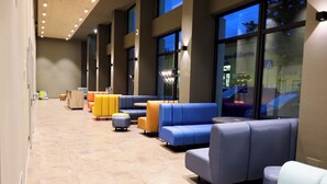 A modern lobby with blue and yellow seating, large windows, and a tiled floor. - a&o Hostel Firenze Campo Di Marte (Florence)