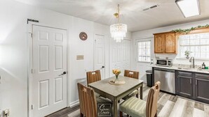 A dining area with a table, chairs, a chandelier, and a kitchen with cabinets and a microwave. - Greenleaf Comfort Retreat 4 Beds Decatur (Decatur)
