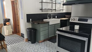 A modern kitchen with a black and white patterned floor, stainless steel appliances, and a black backsplash.
