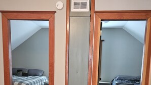 A room with a sloped ceiling, wooden flooring, and two beds with different bedding styles.