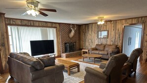 Ein Wohnzimmer mit Kamin, Ledersofas, einem Couchtisch und einem Fernseher.