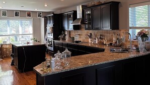 A modern kitchen with dark cabinetry, granite countertops, and recessed ceiling lights. - Awesome home 17th hole for the Memorial Tournament! Great for corporate outing. (Dublin)