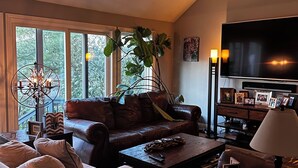 A living room with a brown leather sofa, a white sofa, a coffee table, and a TV. There is a plant, a lamp, and a picture frame on the coffee table. - Awesome home 17th hole for the Memorial Tournament! Great for corporate outing. (Dublin)