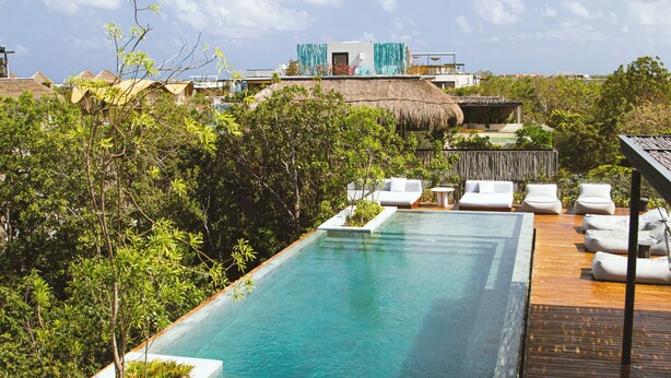 A rectangular swimming pool with a wooden deck and white lounge chairs. - Luxury Penthouse Miraluna 324 (Tulum)