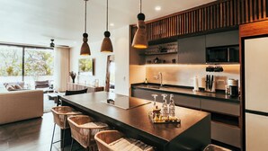 A modern kitchen with a central island, bar stools, pendant lighting, and a view of the outdoors. - Luxury Penthouse Miraluna 324 (Tulum)