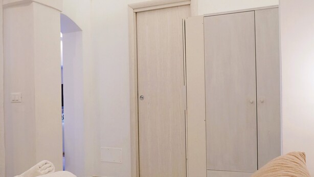 A bedroom with a bed, two pillows, a wardrobe, and a window with a view. - La Casetta in Pietra - Arcuève (Ostuni)