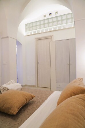 A bedroom with a bed, two pillows, a wardrobe, and a window with a view. - La Casetta in Pietra - Arcuève (Ostuni)