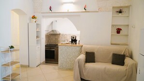 A compact kitchen with a built-in stove, a small island, and a white cabinet. - La Casetta in Pietra - Arcuève (Ostuni)