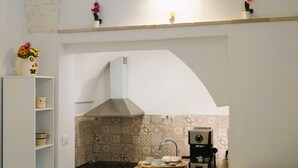 A kitchen with a modern stove, a coffee machine, and a tray with cups and saucers. - La Casetta in Pietra - Arcuève (Ostuni)