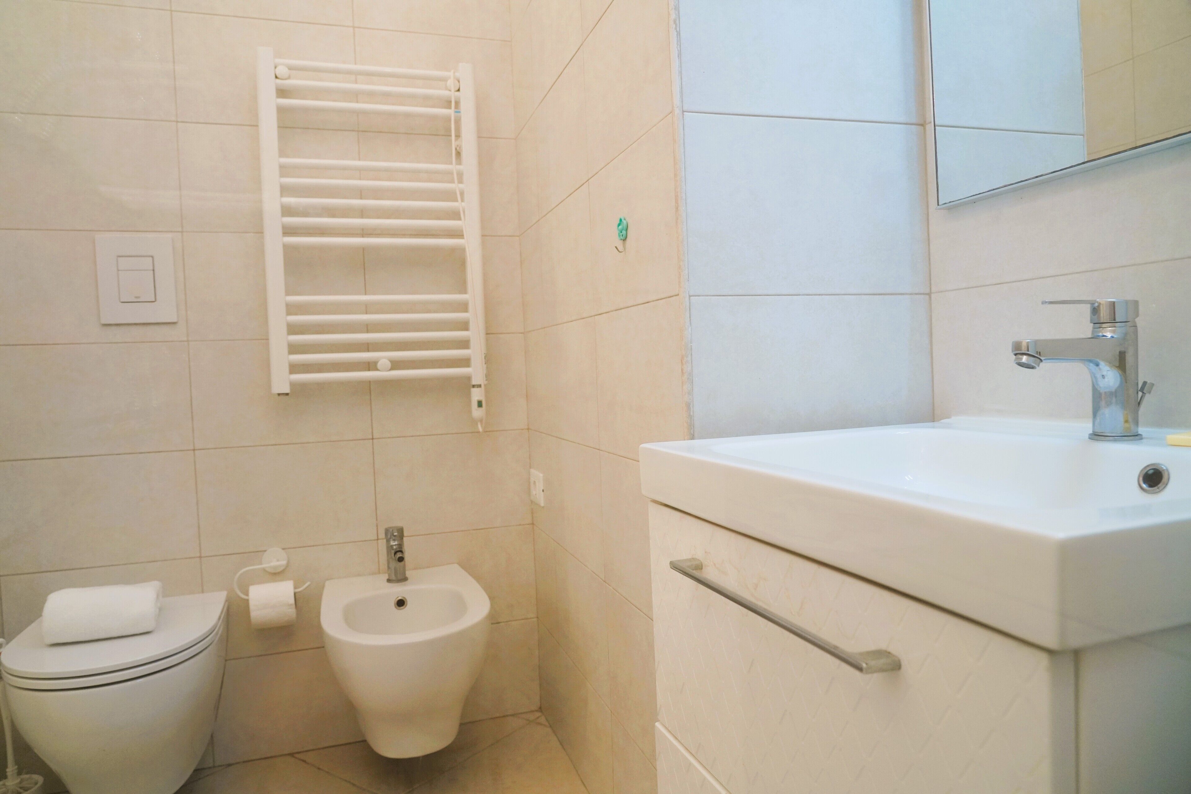 Un bany amb vàter, bidet i rentapelats amb un mirall a la part superior.