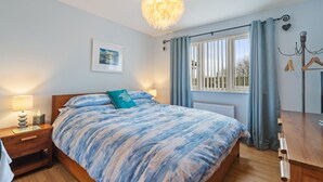 A bedroom with a bed, bedside table, lamp, and a window with curtains.