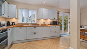 A modern kitchen with white cabinets, a wooden countertop, and a built-in oven.