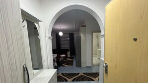 A hallway with a wooden door, a white wall, and a patterned rug on the floor. - Beautiful 2-bedroom Flat sea View Durres (Rrashbull)