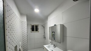 A modern bathroom with a shower, two sinks, a toilet, and a mirror. - Beautiful 2-bedroom Flat sea View Durres (Rrashbull)