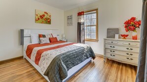 Un dormitorio con cama, cómoda, ventana y un cuadro en la pared.