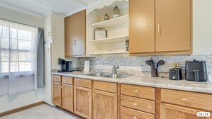 Una cocina moderna con armarios de madera, encimera de mármol, un lavamanos y varios electrodomésticos.