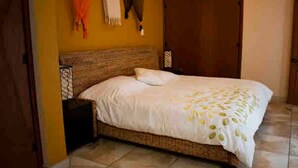 Un dormitorio con una cama, una mesita de noche, un armario y una pared con una toalla colgada.