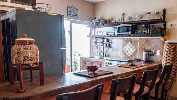 Una cocina con barra, equipada con refrigerador, microondas y diversos electrodomésticos.