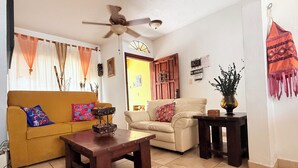 Una sala de estar con sofá, sillón, mesa de centro y ventilador de techo.