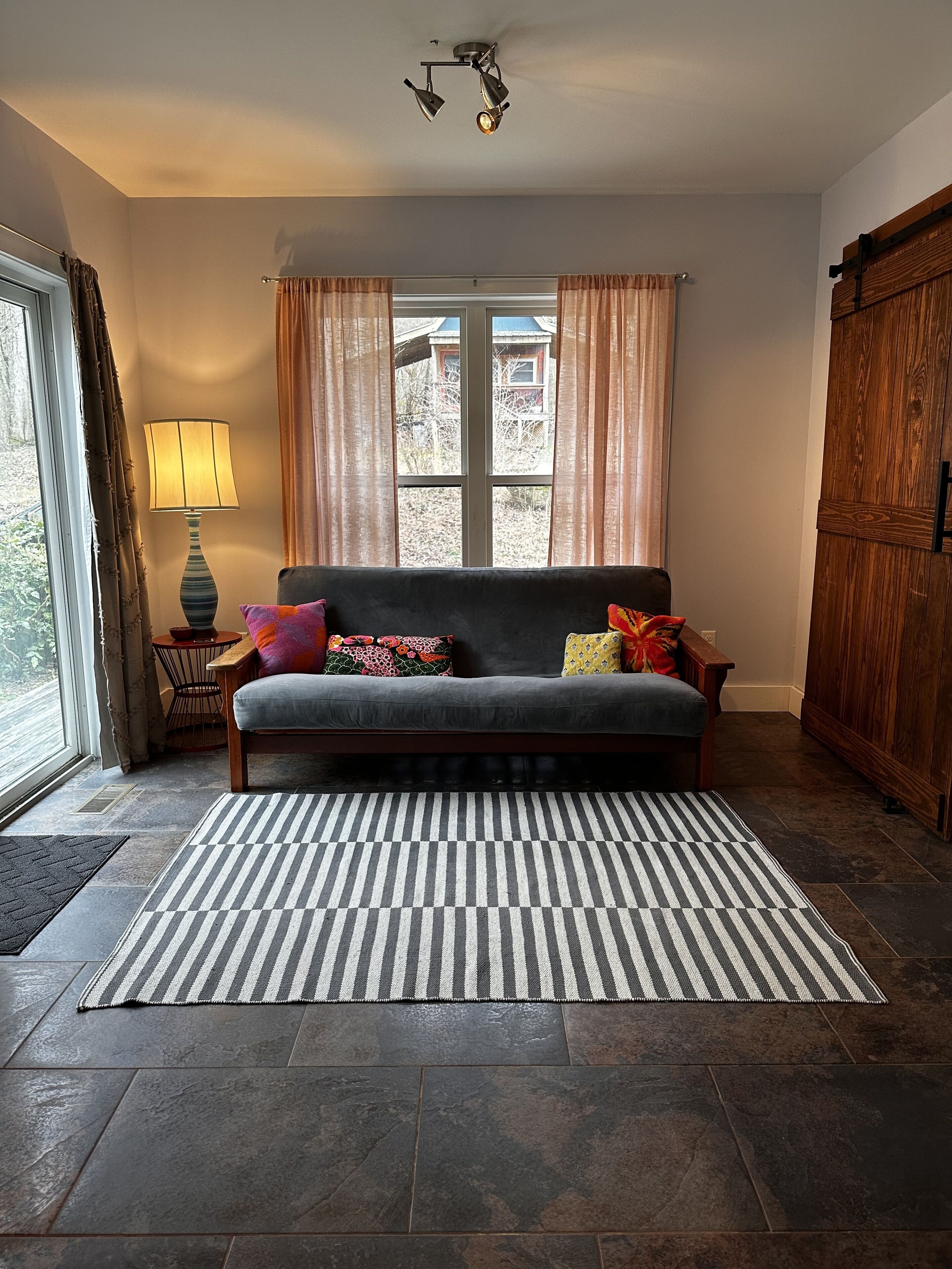 A living room with a sofa, patterned rug, and a window with curtains.