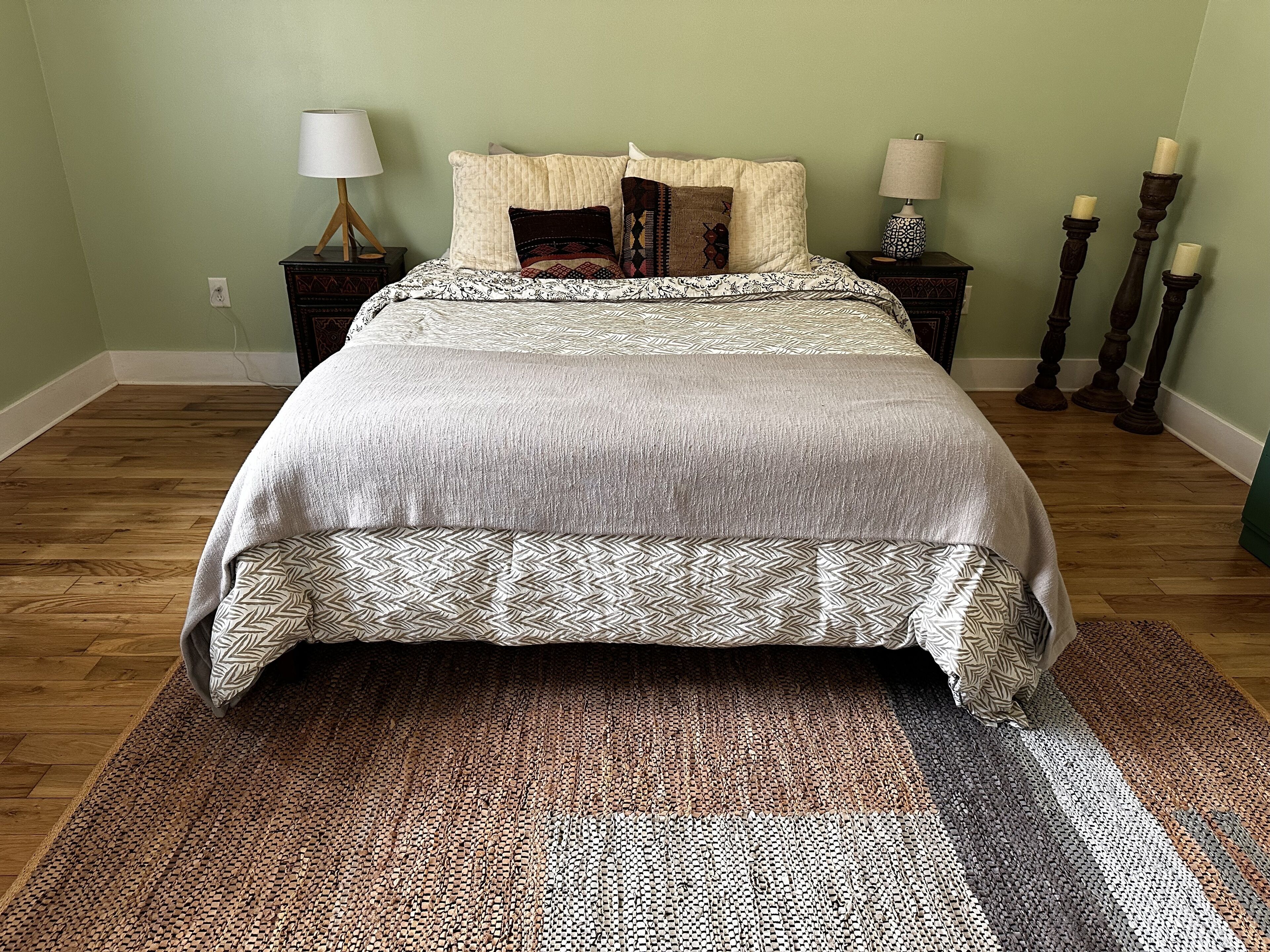 A bedroom with a bed, two nightstands, and three candles.