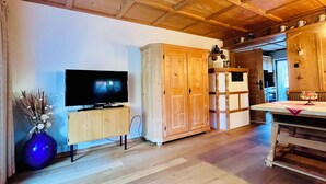 Un intérieur en bois avec un téléviseur posé sur un meuble, une grande armoire et un coin cuisine.