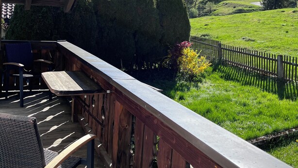 Une terrasse en bois offrant une vue sur un champ verdoyant et des montagnes.