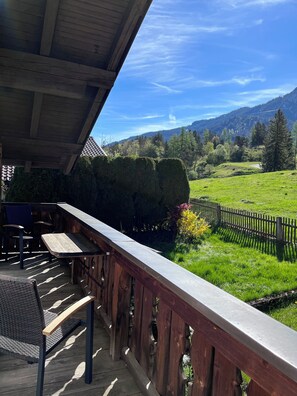 Une terrasse en bois offrant une vue sur un champ verdoyant et des montagnes.