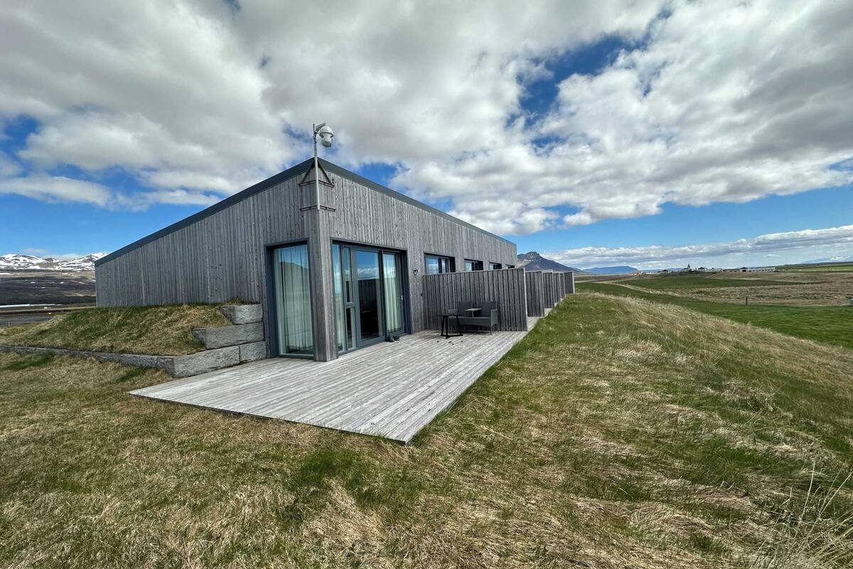 A modern building with a flat roof, large windows, and a wooden deck.