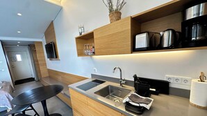 A modern kitchen with a double sink, wooden cabinets, and a built-in oven. - Eiðhús Apartments (Eyja- og Miklaholtshreppur)