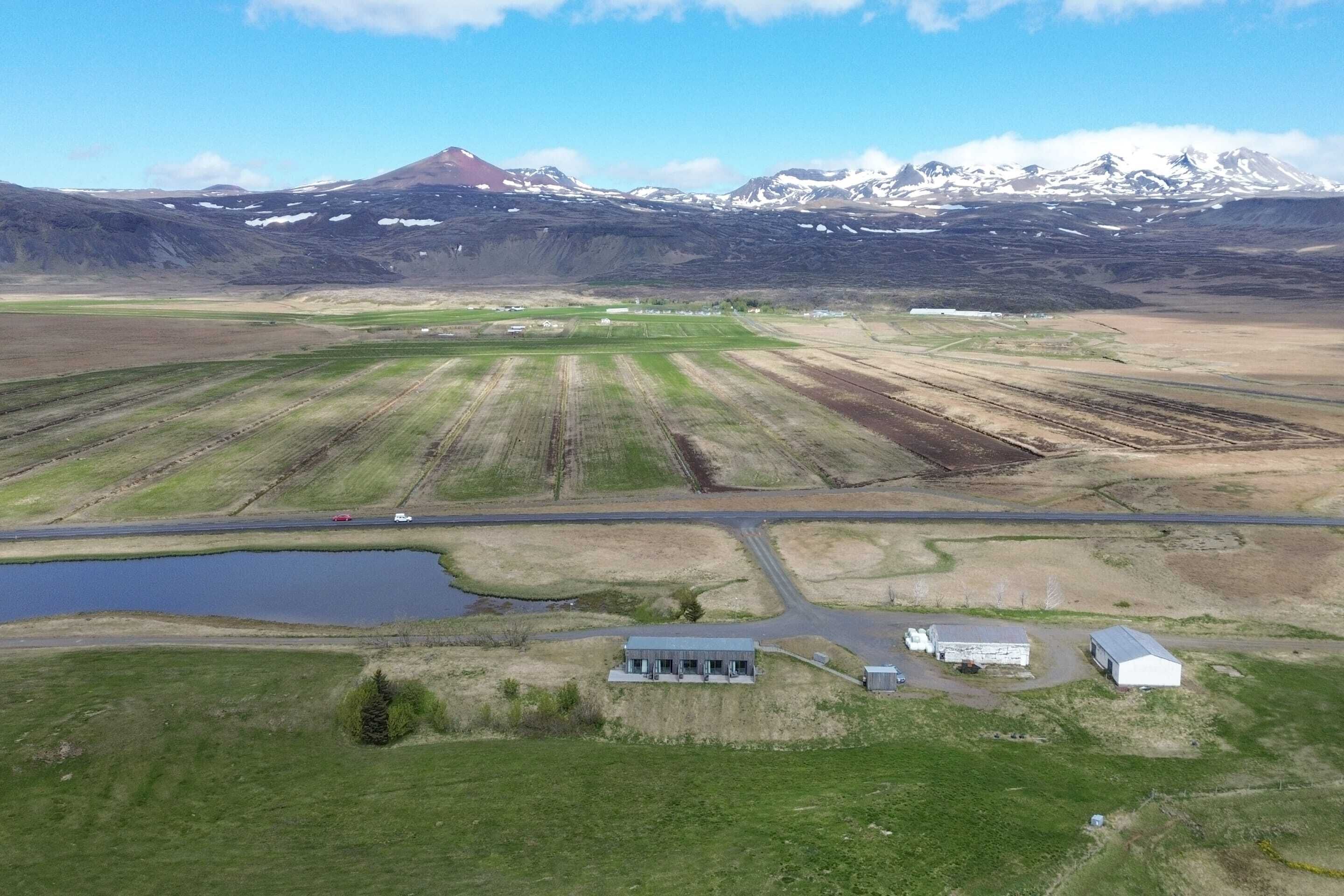 An aerial view of a rural landscape with fields, a small body of water, and a few buildings.