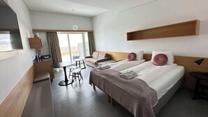 A modern hotel room with a large bed, a sofa, a dining table, and a TV. - Eiðhús Apartments (Eyja- og Miklaholtshreppur)